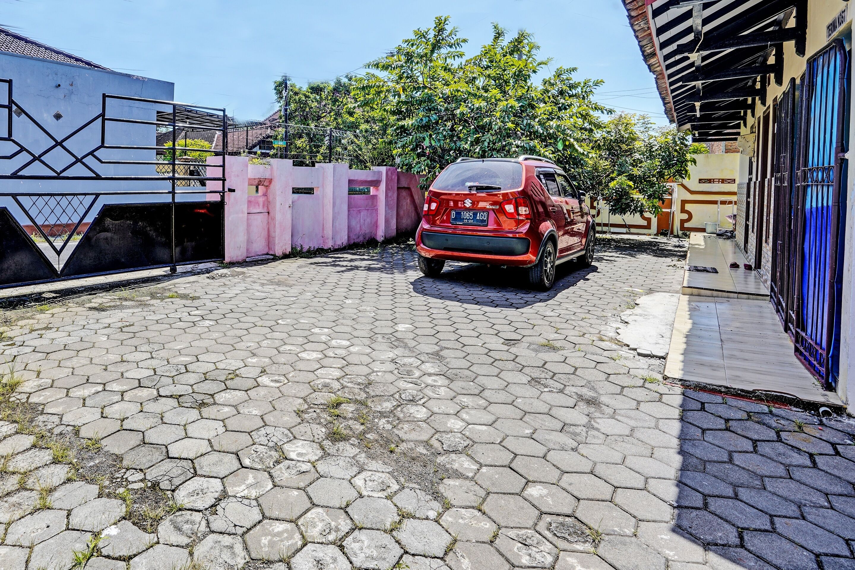 Un coche rojo estacionado en un patio empedrado con un diseño de baldosas hexagonales.