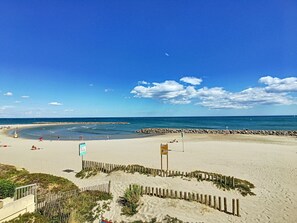 Una playa con una cerca de madera, un letrero y un litoral rocoso.