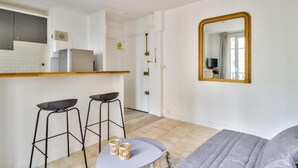 Et moderne køkken med en hvid bordplade, to sorte barstole og et rundt bord med to stearinlys.