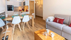 Un salon moderne avec un canapé gris, une table basse en bois et un coin repas comprenant une table et des chaises en bois.