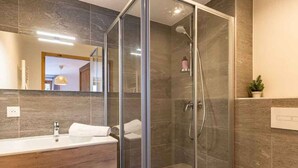 Une salle de bain moderne avec une douche à parois de verre, un meuble-lavabo en bois et un grand miroir.