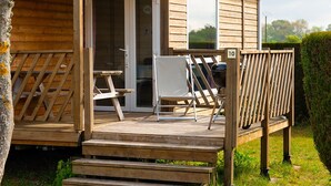 Een houten hut met een terras, een tafel en twee stoelen.