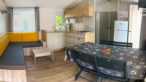 Een knus woongedeelte met een kitchenette, een eethoek en een zithoek met een bank.