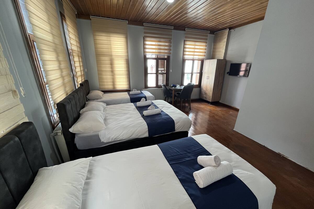 Una habitación de hotel con cuatro camas, un escritorio y televisión.