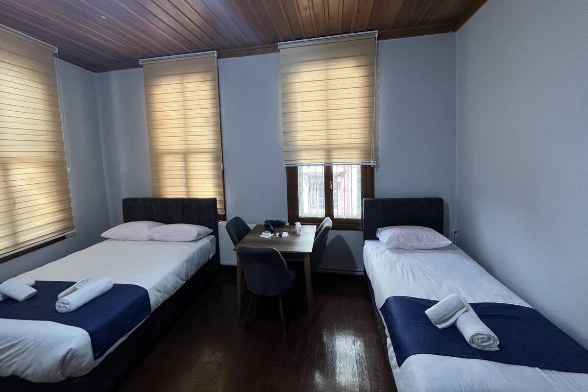 Una habitación con dos camas individuales, una mesita y una silla.