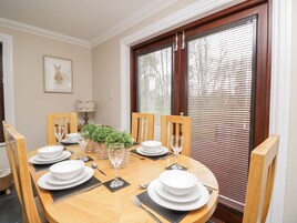Comedor con una mesa de madera redonda dispuesta para seis personas, rodeado de sillas de madera.