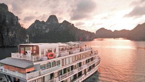 A multi-deck river cruise ship with outdoor seating areas and a covered deck. - Arcady Boutique Cruise (Tuan Chau)