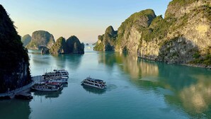 A river with boats docked on the left, surrounded by rocky cliffs. - Arcady Boutique Cruise (Tuan Chau)