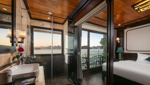 A modern bathroom with a large sink, mirror, and shower. It features a wooden ceiling and large windows offering a view of the sea. - Arcady Boutique Cruise (Tuan Chau)