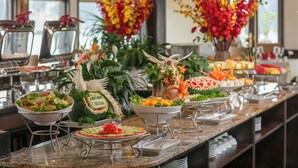 A buffet with various food items and decorative plants. - Arcady Boutique Cruise (Tuan Chau)