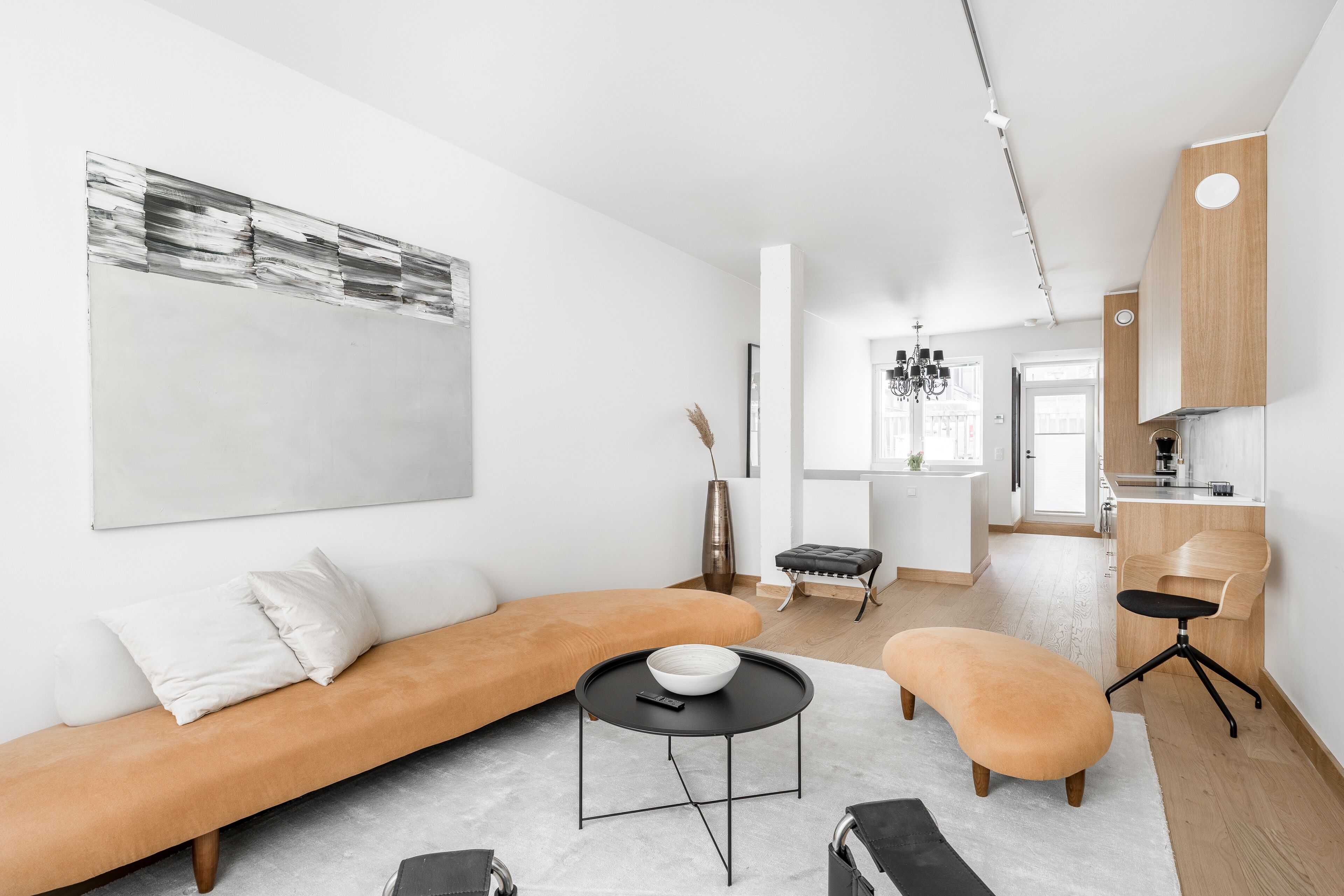 Uma sala de estar moderna com um sofá, uma mesa de centro redonda e uma área de jantar com uma cadeira e uma mesa.