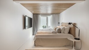 Un dormitorio con cama, mesita de noche, lámpara, televisor y ventana con cortinas.