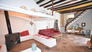A cozy living room with a fireplace, red leather sofa, and a staircase leading to an upper level. - Villa con Excelente Piscina (Sóller)