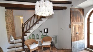 A staircase with wooden railings, two wicker chairs with cushions, a hanging light fixture, and a rustic wooden door. - Villa con Excelente Piscina (Sóller)