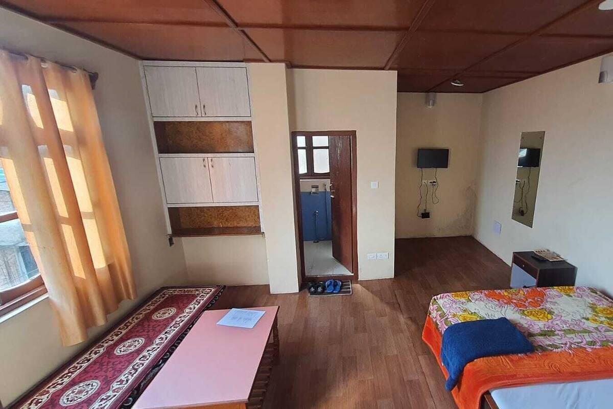 A room with a bed, a desk, a wardrobe, a mirror, and a television.