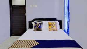 A bed with a white and blue bedspread, two pillows with geometric patterns, and a dark blue throw. - OYO Life 92353 Purnama Syariah Guest House (Malang)