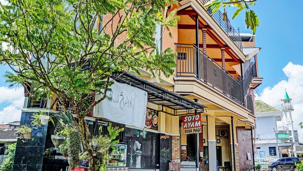 A multi-story building with a balcony, a sign for 'Soto Ayam Buka Pagi', and a mosque in the background. - OYO Life 92353 Purnama Syariah Guest House (Malang)