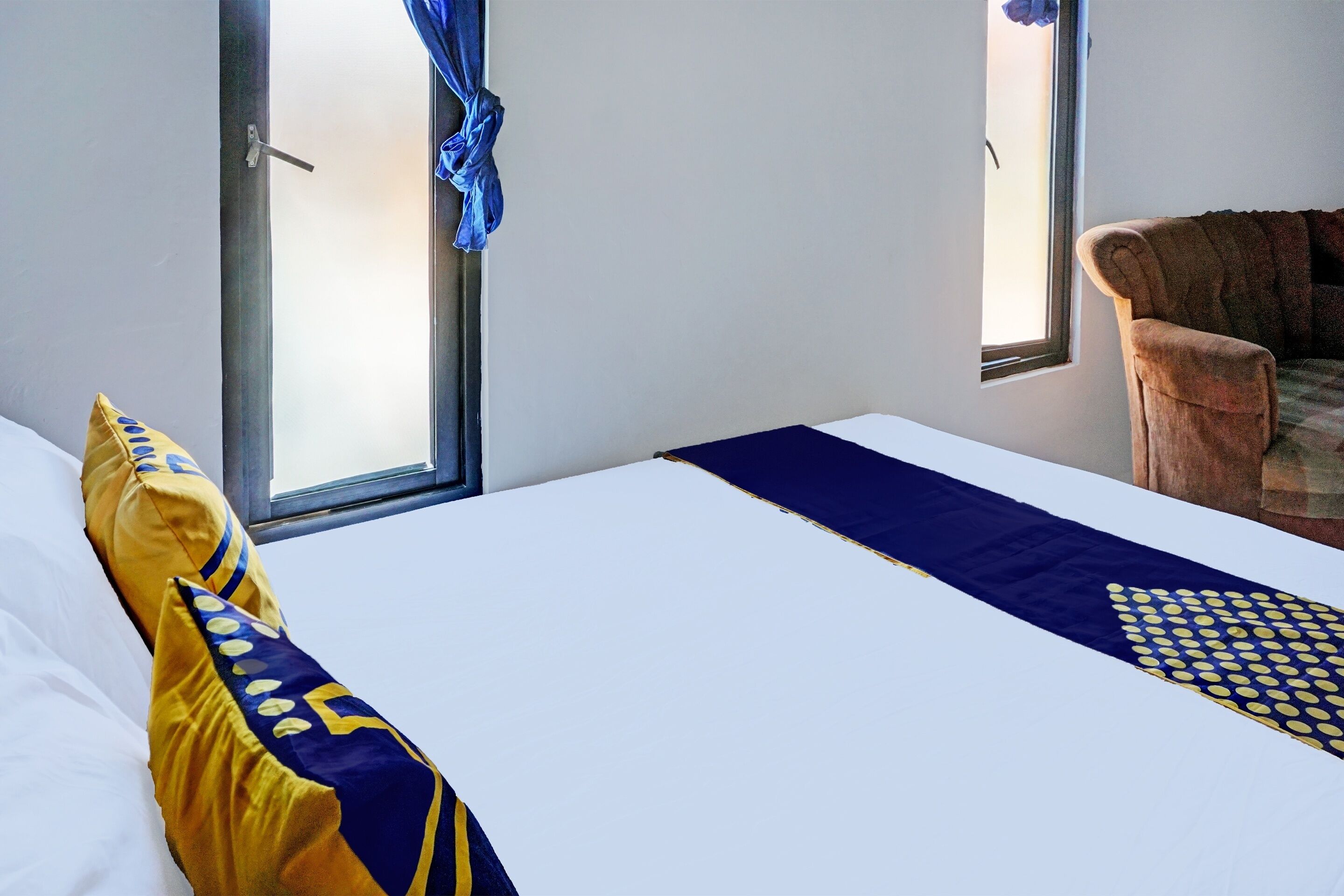 Una habitación de hotel con una cama, una ventana y una silla.