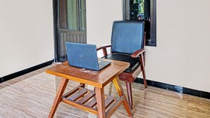 A wooden table with a laptop and a chair with a cushioned seat. - OYO Life 92353 Purnama Syariah Guest House (Malang)