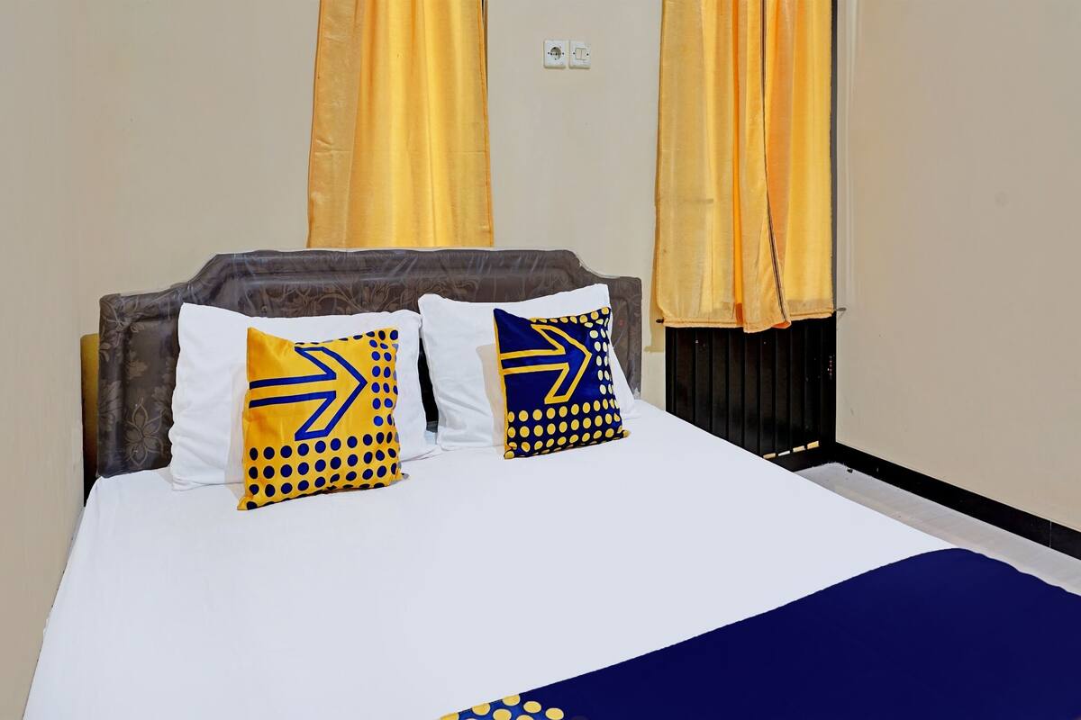 Una cama con ropa blanca y dos almohadas decorativas de diseños geométricos.