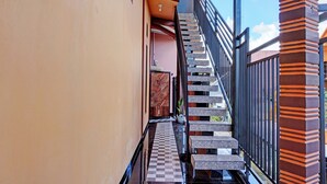 A narrow corridor with a checkered floor leading to a staircase with a black railing. - OYO Life 92353 Purnama Syariah Guest House (Malang)