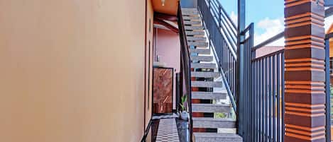 A narrow corridor with a checkered floor leading to a staircase with a black railing.