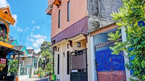 A street view with a two-story building, a gated entrance, and a blue gate with decorative patterns. - OYO Life 92353 Purnama Syariah Guest House (Malang)