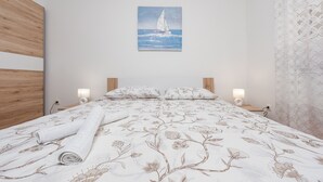 Un dormitorio con una cama, un cuadro de un velero y dos lámparas de noche.