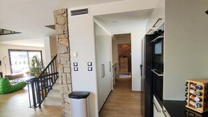 Una cucina moderna con forno integrato, microonde, un armadietto in legno e un cestino per i rifiuti.