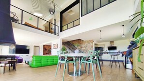 Un'ampia zona giorno con un divano verde, un tavolo da pranzo con sedie e una cucina sullo sfondo.