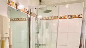 Un baño con ducha de vidrio, lavamanos e inodoro.