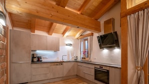 A modern kitchen with wooden beams, a built-in oven, and a window with curtains.