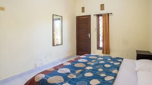 A room with a bed, a door, a small window, and a wall-mounted mirror. - Jero Harum Homestay (Tabanan)