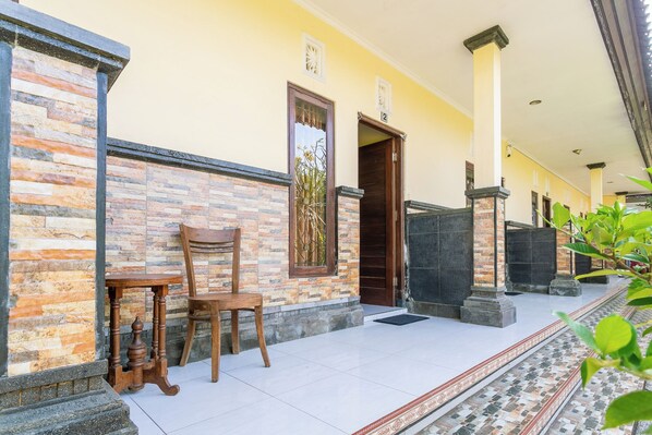 A building with a stone facade, a wooden chair, and a tiled entrance area.