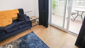 A modern living room with a dark blue sofa, a wooden coffee table, and a blue rug. - 50A Lloyd Street West (Llandudno)