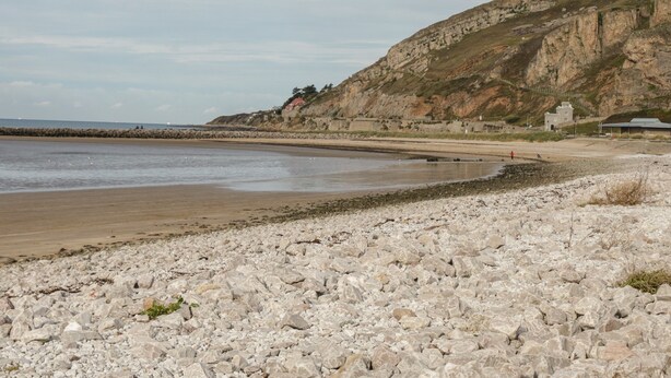 A rocky beach with a rocky shoreline, a small building, and a cliff. - 50A Lloyd Street West (Llandudno)