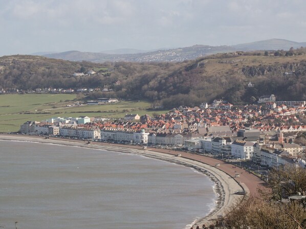 A coastal town with a beach, buildings, and hills in the background. - 50A Lloyd Street West (Llandudno)