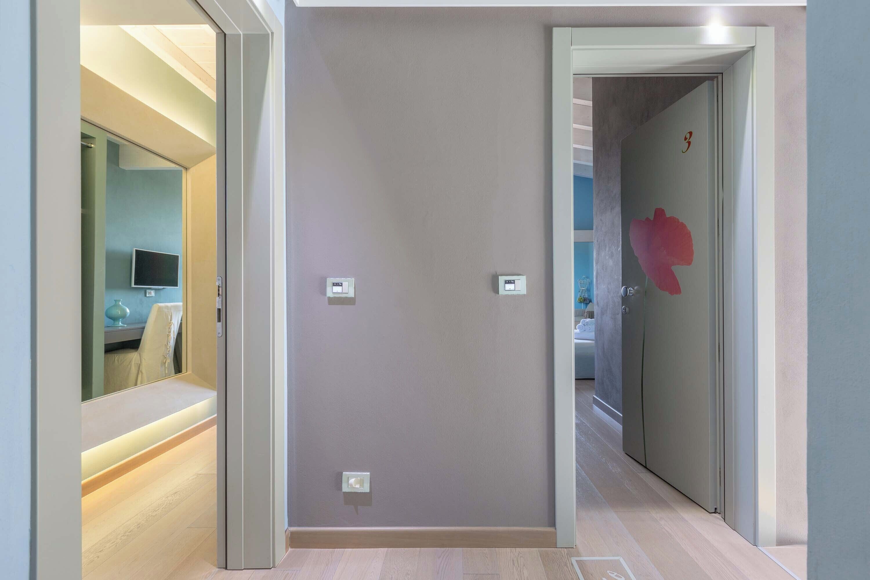 A hallway with a light-colored wall, a door with a red floral decal, and a light switch.