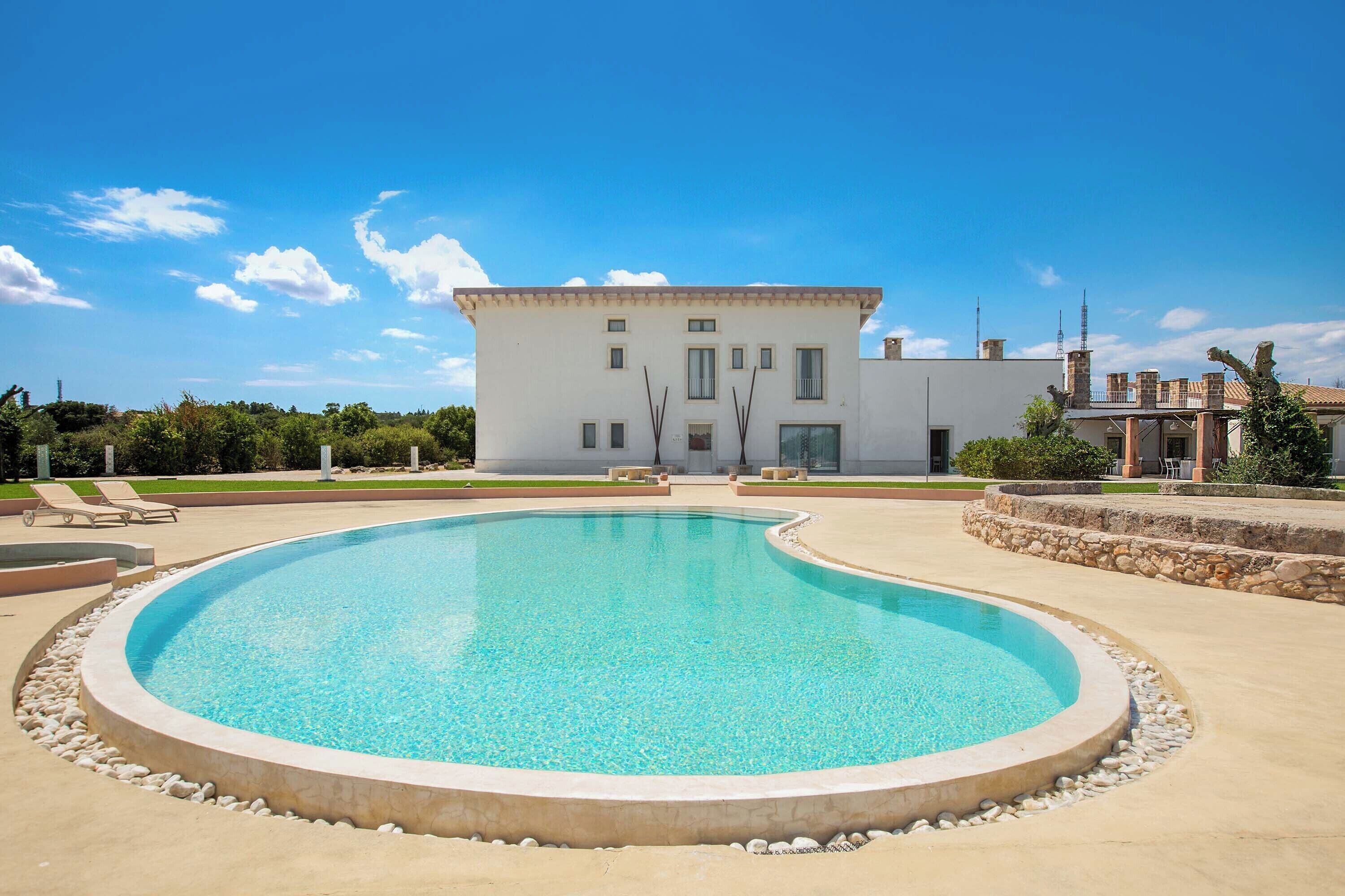 Ein modernes Haus mit Swimmingpool, einem gepflegten Rasen und blauem Himmel.