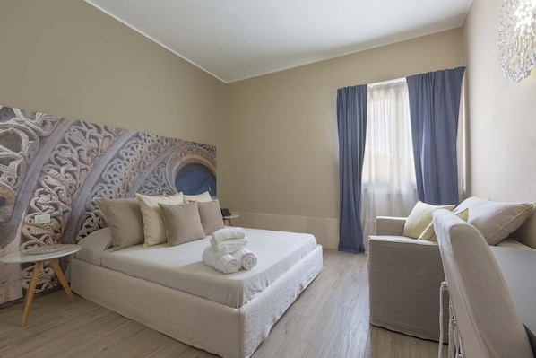 A modern hotel room with a large bed, a sofa, and a small table.