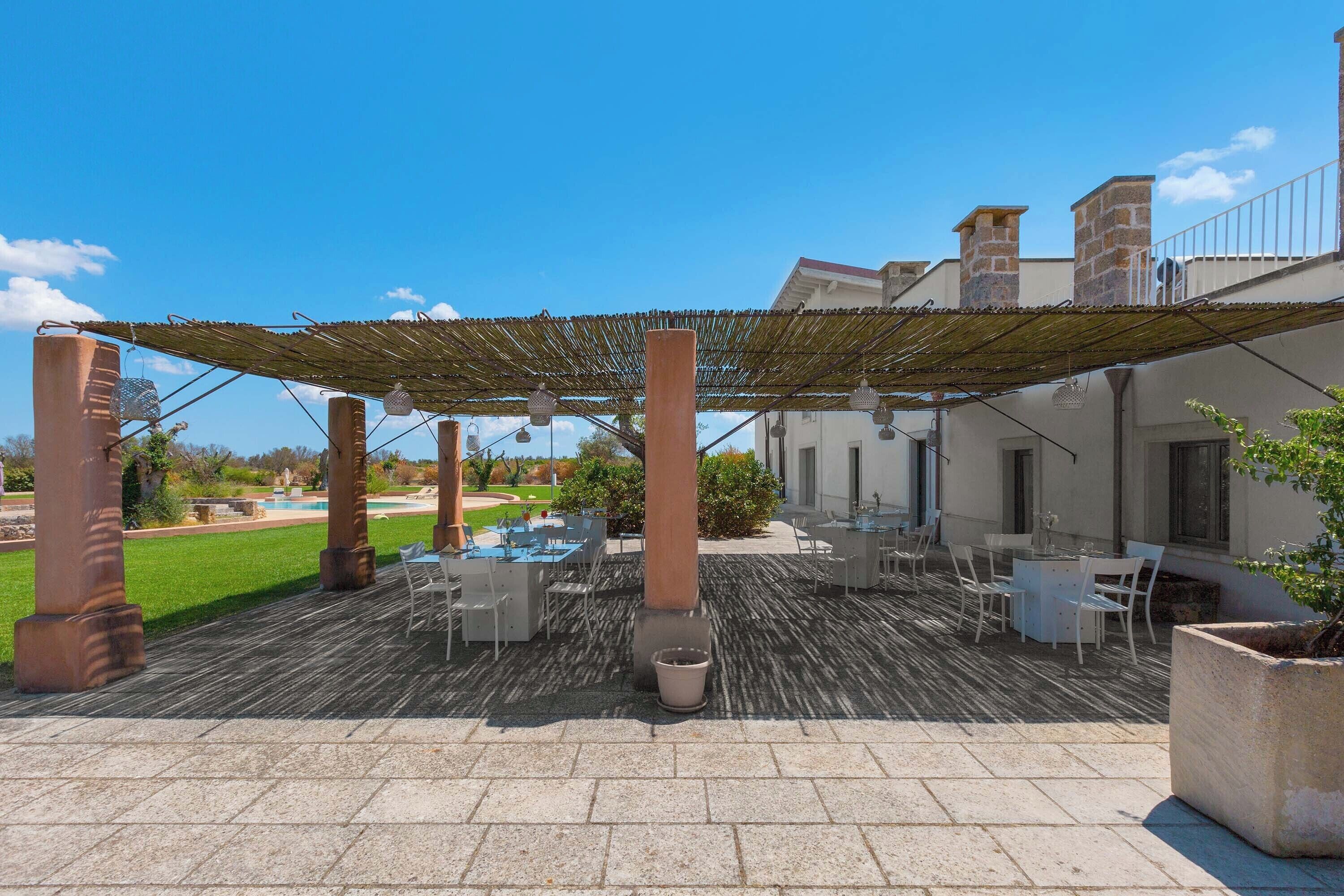 Un espace extérieur aménagé en terrasse, doté d’une pergola, de sièges et offrant une vue sur un jardin.
