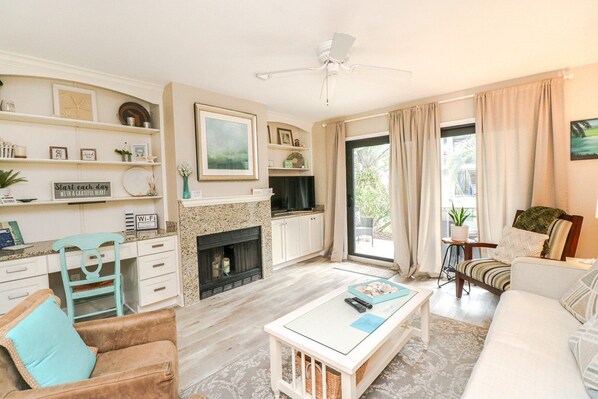 A spacious living room with a fireplace, a dining area, and a seating area with a sofa and armchairs. - Sea Winds 16-Beautiful 2 Bedroom 2.5 Bath Townhome (St. Augustine)