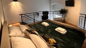 A bedroom with a bed, pillows, a green patterned bedspread, a small plant, and a mounted TV. - 2 room apartment in a historic building in the old town of Goslar (Goslar)