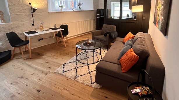 A modern living room with a sofa, coffee table, and a desk with a chair. - 2 room apartment in a historic building in the old town of Goslar (Goslar)