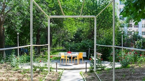 A garden with a metal pergola, a bench, and a table with chairs.