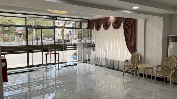 A clean, modern lobby with a glass entrance, two wicker chairs, and a polished marble floor.
