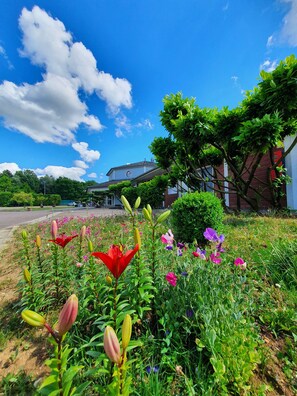 A garden with various flowers and a building in the background. - Eqynox Hôtel (Marolles)