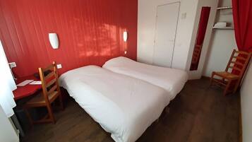 Una habitación con cama, dos sillas, un escritorio y un armario.