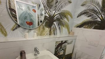 Un baño con un lavamanos blanco, un inodoro y un espejo con marco circular.