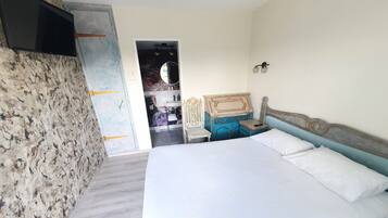 A bedroom with a bed, a dresser, a TV, and a wardrobe.